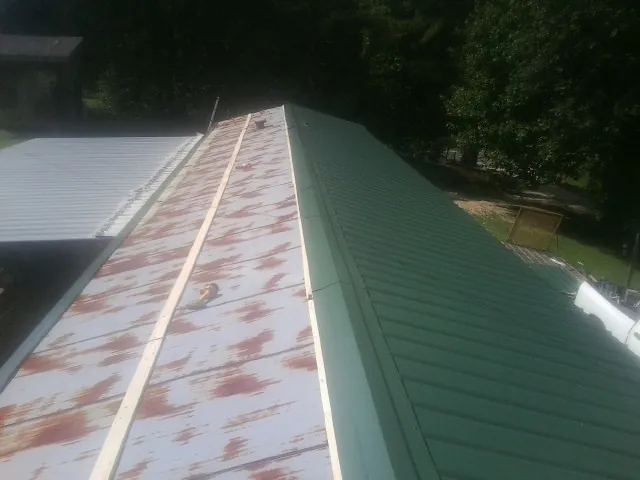 Old rusted panels beside newly installed green metal roofing — Wind Damage Roof Repair by Roofing Brothers in Phenix City