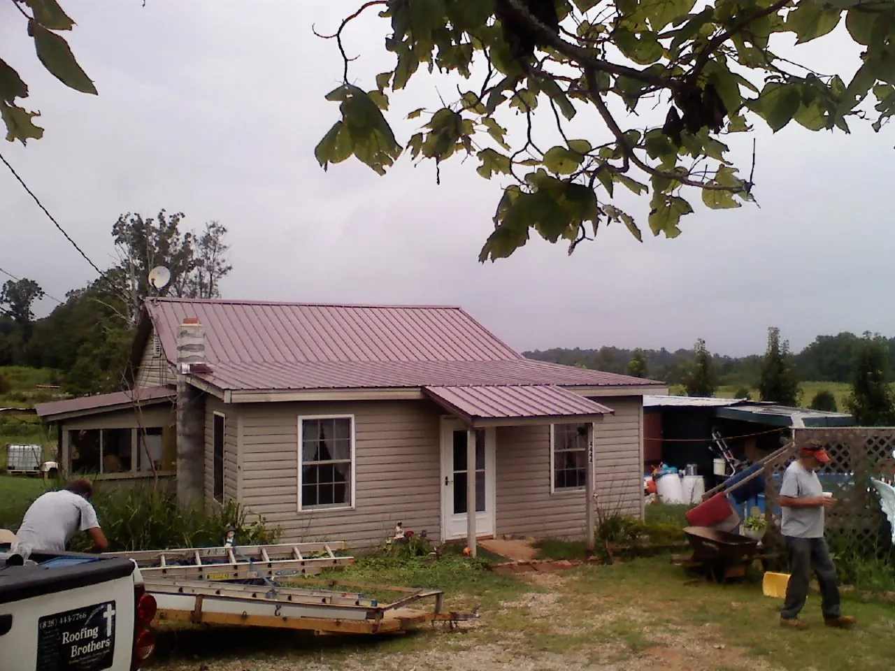 Crew finishing a mauve metal roof on a small farmhouse in Phenix City