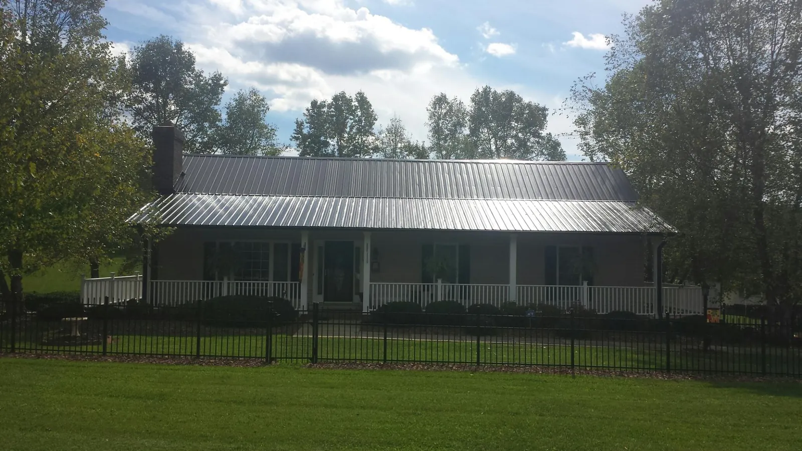 Gray metal roof on a brick ranch with a full width front porch — Gutter Guard Installation work by our crew in Phenix City