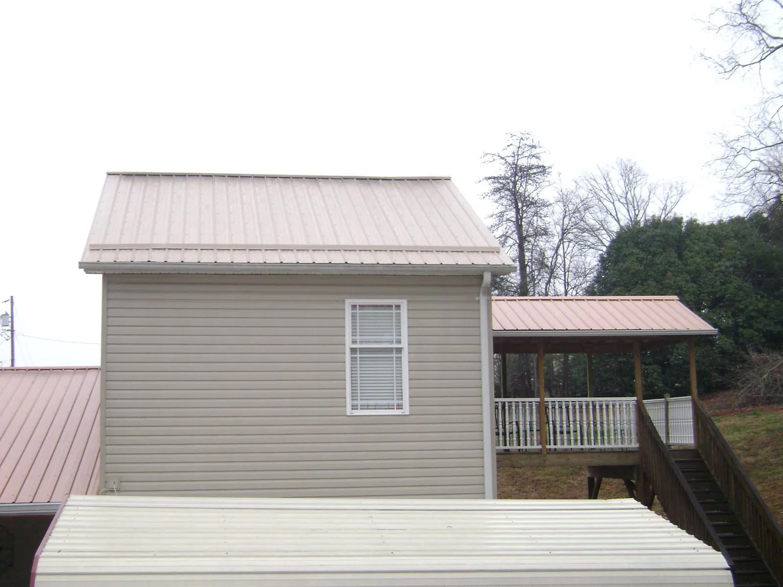 Tan metal roofs on a two story addition and attached porch, from a Roof Replacement job in Phenix City