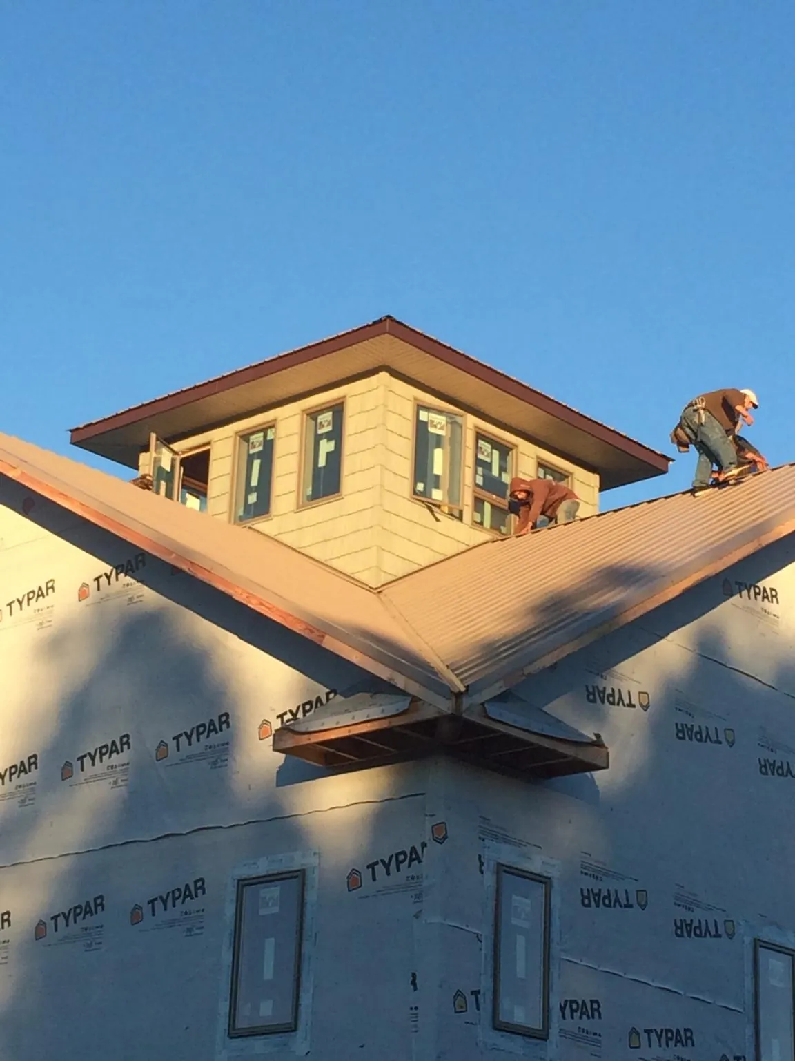 Roofers working around a rooftop cupola on a new metal roof at sunset — Roof Waterproofing in Phenix City by Roofing Brothers
